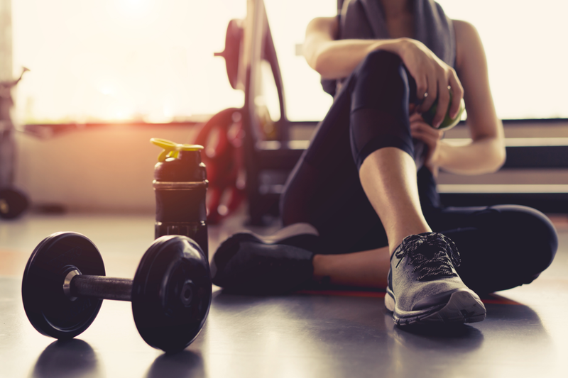 Picture of athletic girl sitting down next to hand weights.