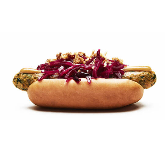Vegan hot dog from Ikea with red shredded beets crispy onions, and horse radish mustard in a bun.